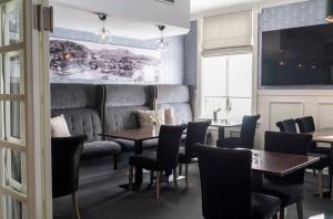 a restaurant with tables and chairs and a couch at Grand Hotel Flekkefjord in Flekkefjord