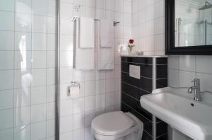 La salle de bains blanche est pourvue de toilettes et d'un lavabo. dans l'établissement Grand Hotel Flekkefjord, à Flekkefjord