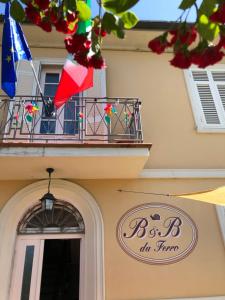 a sign on a building with a balcony and flags at B & B Da Ferro in Massarosa