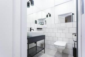 a white bathroom with a sink and a toilet at Niebieski apartament Teatralna in Katowice