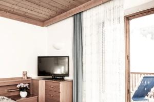 un salon avec une télévision et une grande fenêtre dans l'établissement Bergfrieden Apartment 2 B, à Alpe di Siusi