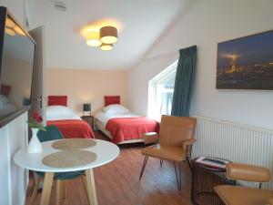 a small room with two beds and a table and chairs at Bed and Breakfast Oosterpark in Harlingen