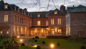 a large brick building with lights in the yard at les Myrrhophores et Spa, Chambres d'Hôtes et Gîtes de charme in Abbeville