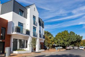 een wit gebouw aan de kant van een straat bij Hotel Krige in Stellenbosch