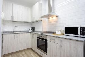 eine Küche mit weißen Schränken und einer Mikrowelle in der Unterkunft Home2Book Charming Apartment Santa Cruz, Wifi in Santa Cruz de Tenerife