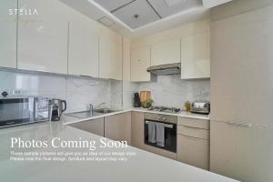 an image of a kitchen with white cabinets at Stella Stays Charming 1 BDR Dubai JVC Private Balcony in Dubai