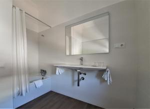 Baño blanco con lavabo y espejo en Hostal Canigó, en El Pont de Suert