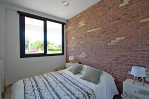 Un dormitorio con una pared de ladrillo y una cama en Sun&Beach Carihuela, en Torremolinos