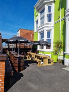 a patio with picnic tables and umbrellas in front of a building at The Beechfield Hotel in Blackpool