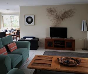 a living room with a couch and a tv at Nambucca Beach House in Nambucca Heads