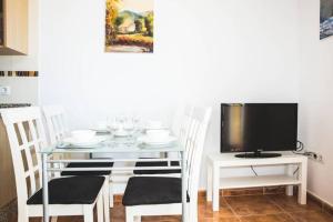 ein Esszimmer mit einem Tisch mit Stühlen und einem TV in der Unterkunft Apartamento con vistas al mar en Pedregalejo playa in Málaga