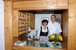 Un uomo e una donna in piedi dietro un bancone di Hotel Helga a Seefeld in Tirol