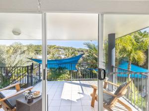 an open door to a balcony with palm trees at Dolphin Lagoon Luxury Escape in Salamander Bay