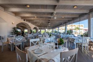 ティガキにあるONEIRO Boutique Hotelの白いテーブルと白い椅子、テーブルサーチャー付きのレストラン