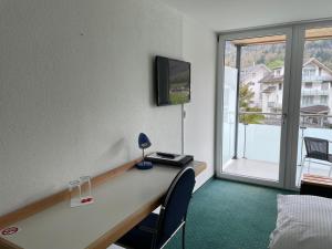 a room with a desk and a large window at Hotel Hahnenblick in Engelberg