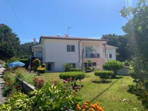 una piccola casa bianca con un cortile fiorito di AFIFE "Porta da Alegria" a Viana do Castelo