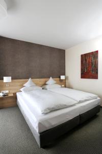 a bedroom with a large white bed and a painting at Hotel-Restaurant Vogthof in Aalen