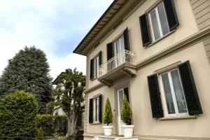 ein Haus mit schwarzen Fensterläden und einem Balkon in der Unterkunft Villa La Tuia B&B in Lucca