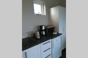 una cucina con mobili bianchi e un forno a microonde di Strýta Apartment 3 a Ölfus