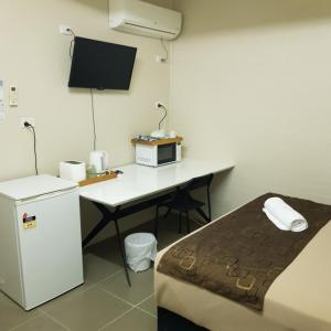 a room with a desk with a microwave and a refrigerator at Kalua Motel in Bundaberg