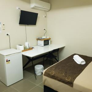 a hotel room with a bed, desk and refrigerator at Kalua Motel in Bundaberg