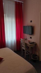 a bedroom with a desk with a television and red curtains at Canto dei Mille in Florence