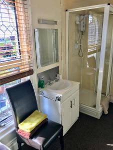 een badkamer met een wastafel, een douche en een stoel bij Claydens in Cleethorpes