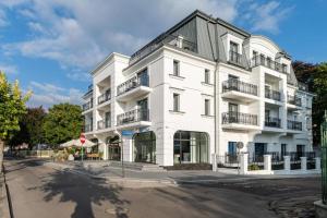 biały budynek z balkonami przy ulicy w obiekcie Luxury Apartments in Residence Maritime w mieście Międzyzdroje