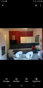 a kitchen with three white chairs and a counter at Les charmilles in Chaudfontaine