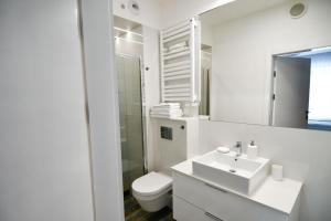 ein weißes Bad mit einem Waschbecken und einem WC in der Unterkunft Blue Sky Apartments Rezydencja Niechorze - 301 in Niechorze