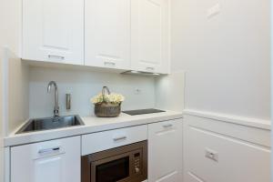 une cuisine avec des armoires blanches et un évier dans l'établissement Amazing Vittoriano, à Rome