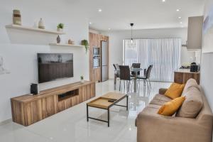 a living room with a couch and a tv and a table at Apartment 5 Ashville Court in Marsalforn