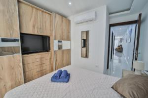 a bedroom with a bed with blue slippers on it at Apartment 5 Ashville Court in Marsalforn