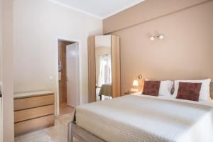 a bedroom with a large white bed and a mirror at Galini Beach Studios and Penthouse in Mesongi