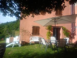 a table and chairs with an umbrella in a yard at L'ALPACA DELLA ROSSA - AGRITURISMO in Genga