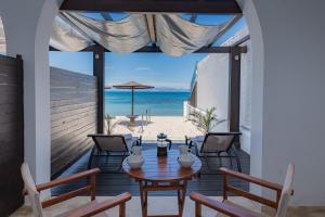 patio ze stołem i krzesłami oraz plażą w obiekcie Galini Beach Studios and Penthouse w mieście Mesongi