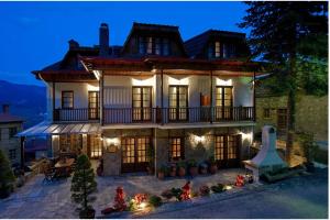 une grande maison avec une véranda éclairée dans l'établissement Hotel Kassaros, à Metsovo