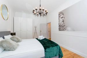 - une chambre avec un lit blanc et un lustre dans l'établissement Apartament na Gdańskiej Starówce, à Gdańsk