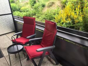 twee rode stoelen op een balkon met uitzicht op een raam bij Ferienwohnung Charlotte in Winterberg