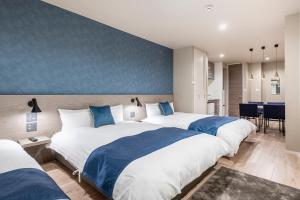 2 łóżka w pokoju hotelowym z niebieskimi ścianami w obiekcie hotel aima w Tokio