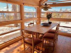uma mesa de madeira e cadeiras num quarto com janelas em Skarehaug - koselig hytte med 3 soverom em Skadeland