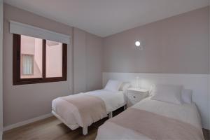 Dos camas en una habitación blanca con ventana. en Sonia´s Beach, en Los Cancajos