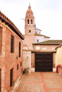 a brick garage with a clock tower in the background at La Casona De Tia Victoria in Rueda