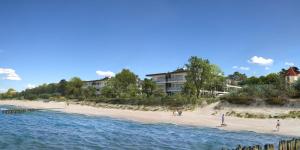 a beach with a group of people standing on the sand at Blue Sky Apartments Rezydencja Niechorze in Niechorze