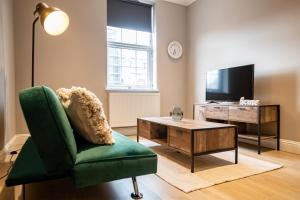 a living room with a green chair and a tv at Deluxe Modern 1&2 Bed Apartments Near Brighton Beach & Station in Brighton & Hove