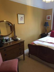 a bedroom with a bed and a dresser with a mirror at Wrangham House in Filey