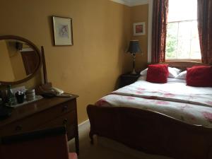 a bedroom with a bed with red pillows and a mirror at Wrangham House in Filey