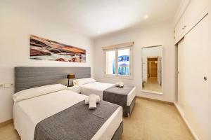 a bedroom with two beds and a large window at villa amfora in Port d'Alcudia
