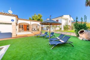 eine Gruppe Stühle auf einem Rasen mit Sonnenschirm in der Unterkunft Villa Amfora by Sealand Villas in Port d'Alcúdia