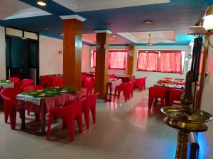 a dining room with red tables and chairs and red chairs at Hotel Silver Sand in Trivandrum